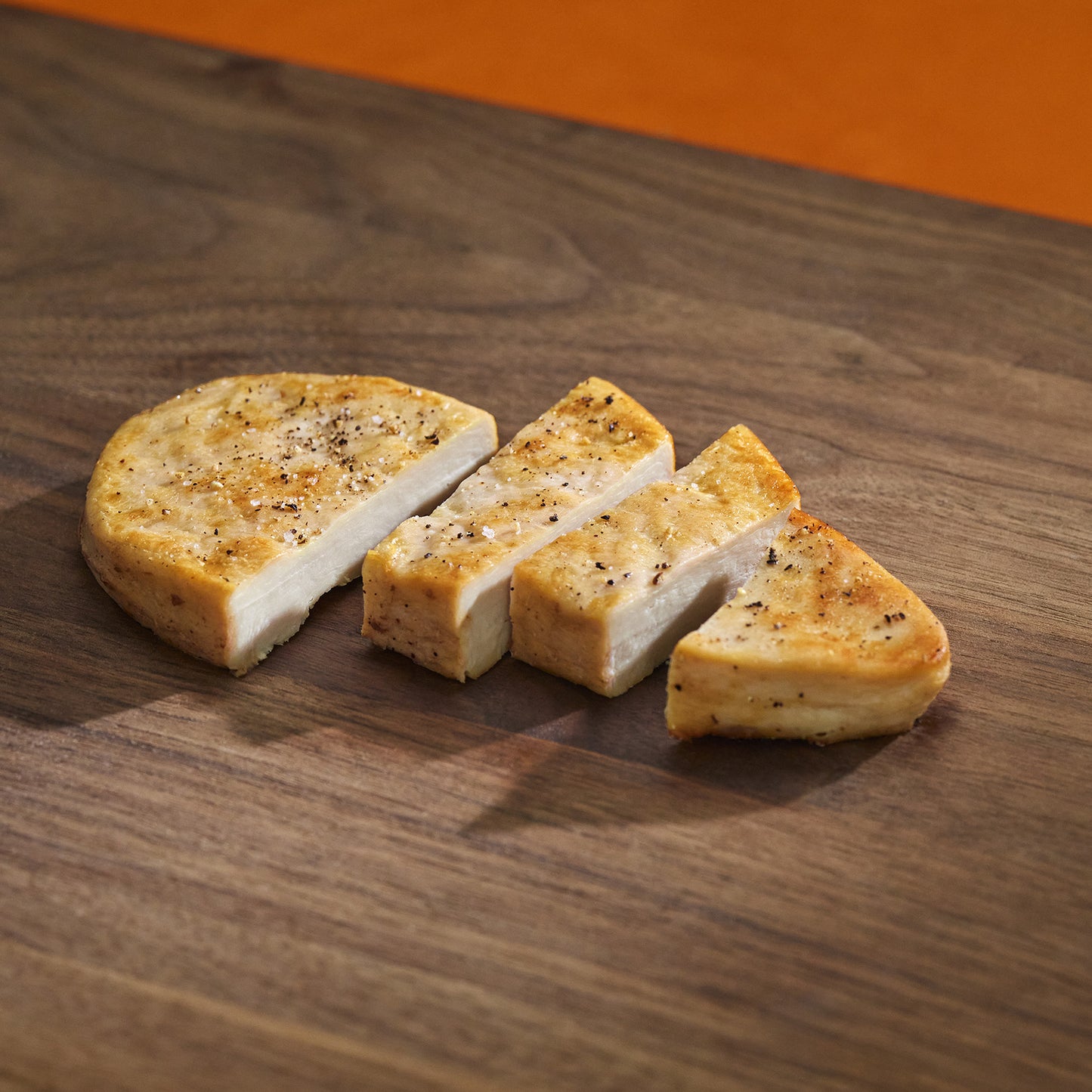 Sliced bread on a wooden surface with an orange background