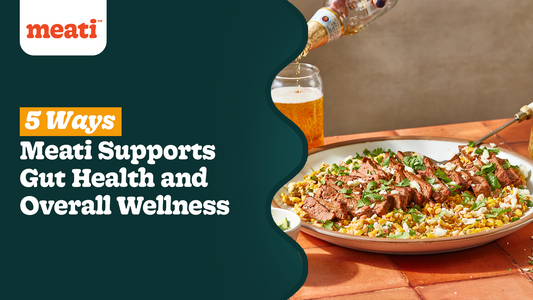 meati classic steak placed on a plate next to a glass with beverage on a wooden table top